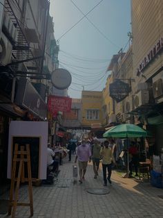 people walking down the street in front of shops and stores with umbrellas on either side