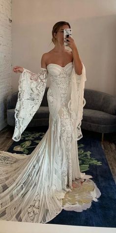 a woman is taking a selfie in her wedding dress while wearing a white gown