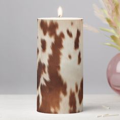 a brown and white candle sitting on top of a table next to a pink vase