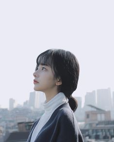 a woman standing in front of a cityscape with her head tilted to the side