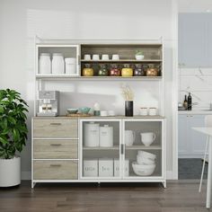 a kitchen with white walls and wooden flooring next to a dining room table filled with chairs