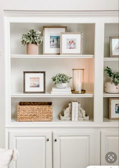 a white bookcase with pictures and plants on it