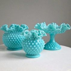 three blue vases sitting on top of a white table