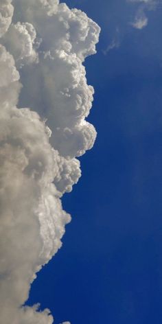 an airplane is flying high in the sky with clouds behind it and blue skies above