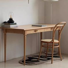 a wooden desk and chair in a room with a lamp on the wall next to it