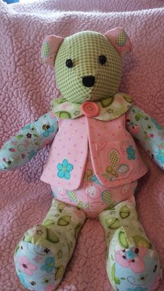 a green teddy bear sitting on top of a pink blanket