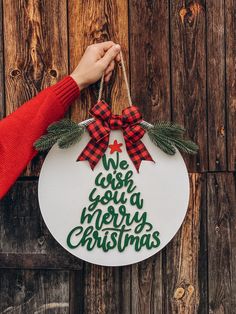 a person holding a christmas ornament with the words we wish you a merry christmas