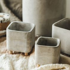 three cement pots sitting on top of a blanket