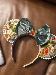 a mouse ears headband with flowers on it and a remote control next to it