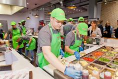 people in green aprons and hats are preparing food