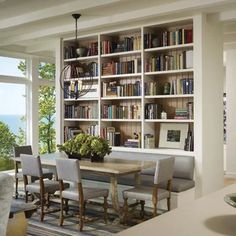 a dining room table and chairs with bookshelves in the background