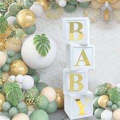 a baby shower is decorated with balloons, greenery and palm leaves on the wall