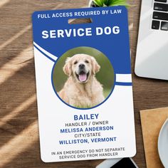 a service dog id card sitting on top of a wooden table next to a laptop