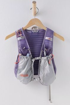 a purple vest hanging on a white wall next to a wooden hanger with clothes