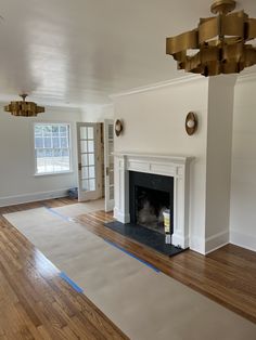 an empty living room with white walls and wood floors, including a fireplace in the center