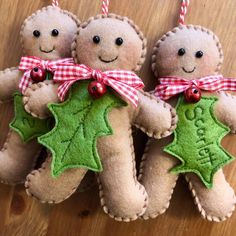 three gingerbread man ornament hanging on a wooden table with red and white checkered ribbon