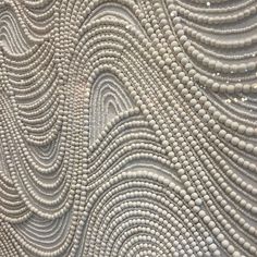 an intricately designed surface with white beads on it's edges and wavy lines in the middle