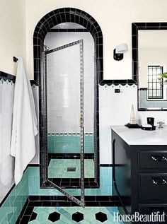 a bathroom with black and white tile on the floor, shower stall and sink area