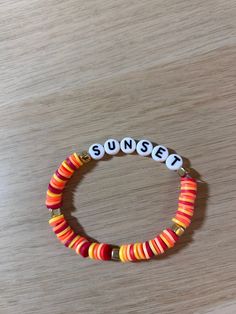 a bracelet with the word sunset written in white letters on it, sitting on top of a wooden table