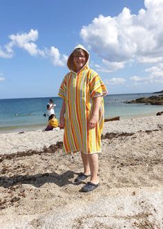 a woman standing on top of a sandy beach next to the ocean wearing a colorful dress