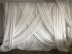 white drapes are hanging from the ceiling in front of a wall that has stairs leading up to it