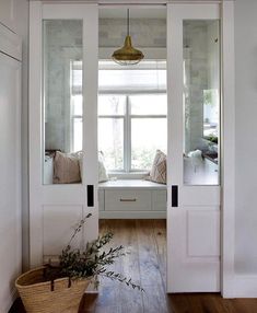 an open door leading to a bedroom with white walls and wood flooring, along with a window seat on the far side