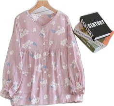 a pink shirt with white flowers on it next to a book