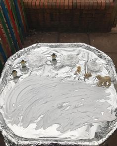 an aluminum pan covered in silver foil with small animals on it's side and some bricks behind it