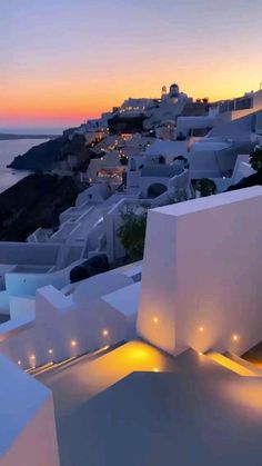 the sun is setting over an ocean and white buildings in oia, paros