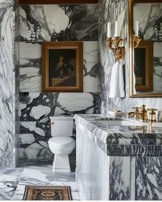 a white toilet sitting next to a sink in a bathroom under two framed pictures on the wall