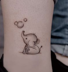 small elephant tattoo on the ankle with bubbles coming out of its trunk and an object floating in the air