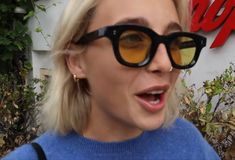 a woman wearing sunglasses and making a funny face in front of a sign that says pop