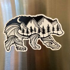 a bear sticker with trees and mountains in the background on a stainless steel refrigerator