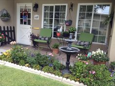 a patio with chairs, table and potted plants in front of the door to a house