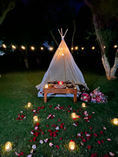 a teepee is lit up with candles and flowers on the grass in front of it