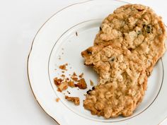 two oatmeal cookies on a plate with one cookie broken off the side