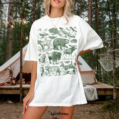 This Unisex garment-dyed t-shirt features a gorgeous set of vintage forest animal, insect and botanical illustrations. It is the perfect gift for environmental conservationists, park rangers, wildlife veterinarians and more! » A B O U T « ‣ This item is made to order using direct-to-garment (DTG) printing technology. This digital process involves the printer inks being jetted or sprayed onto the textile by a print head after the garment goes through a pre-treatment machine to create a stronger bond between garment fibers and the pigmented inks. ‣ This is NOT screen printed NOR do we use heat transfer vinyl (iron-on). ‣ The garment is dyed after it's been constructed, giving it a soft color and texture. » S I Z I N G « ‣ Since we all have different bodies, some find the garments to be eithe Woodland Clothes, Girl Camping, Animals Graphic, Camping Clothes, Park Rangers, Vintage Forest, National Park Shirt, Animal Graphic Tee, Botanical Illustrations