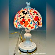 a lamp with mickey mouse on it sitting on top of a white base and yellow cord