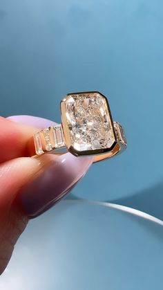 someone is holding an engagement ring with a fancy diamond in it's middle finger