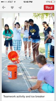 a group of people standing around an orange bucket