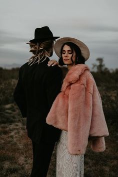 a man and woman dressed in black, white and pink are standing next to each other