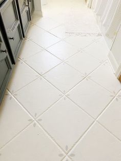 a white tiled floor in a kitchen next to an oven and counter top with cabinets