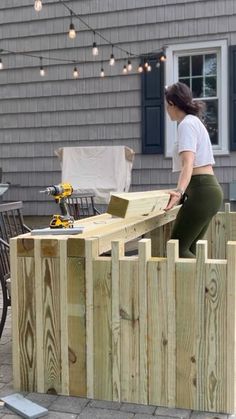 a woman standing on top of a wooden fence