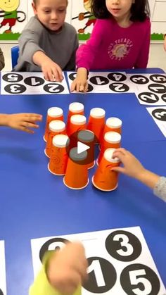 children are playing with numbers on the blue tablecloth in front of them is an orange cup