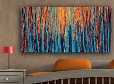 an orange and blue painting hangs above a bed