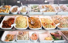 a display case filled with lots of different types of food in bowls and trays