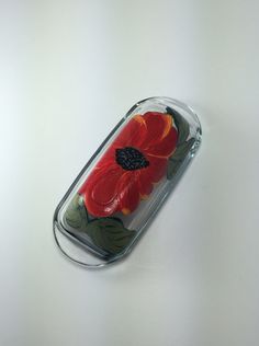 a red flower in a clear case on a white surface