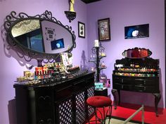 a room with purple walls and an ornate mirror on the wall above a black dresser