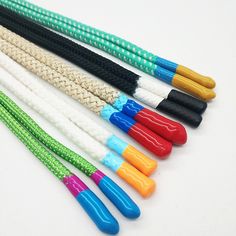 five different colored plastic straws with handles on white table top next to each other