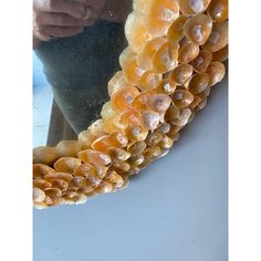 a person holding a mirror with shells on it